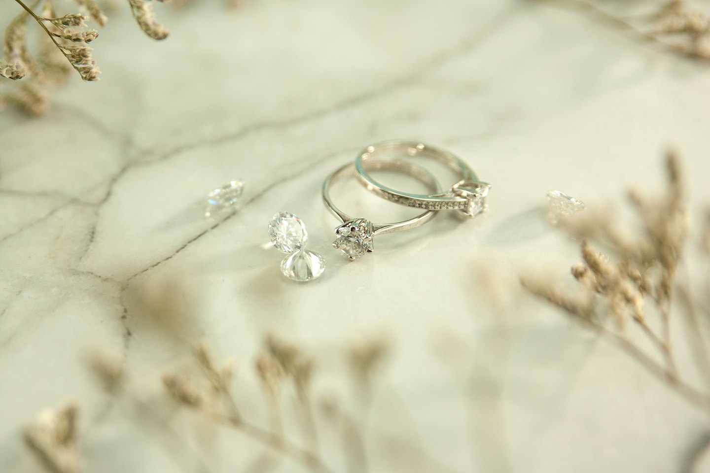 Two diamond rings and loose diamonds on white marble.