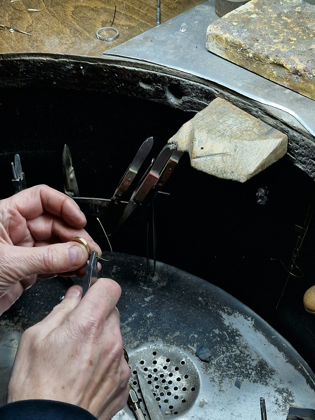 Jeweler uses small pliers to repair a gold ring.