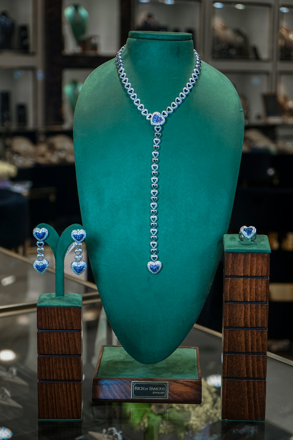 Diamond and blue gemstone jewelry set displayed on velvet stands.